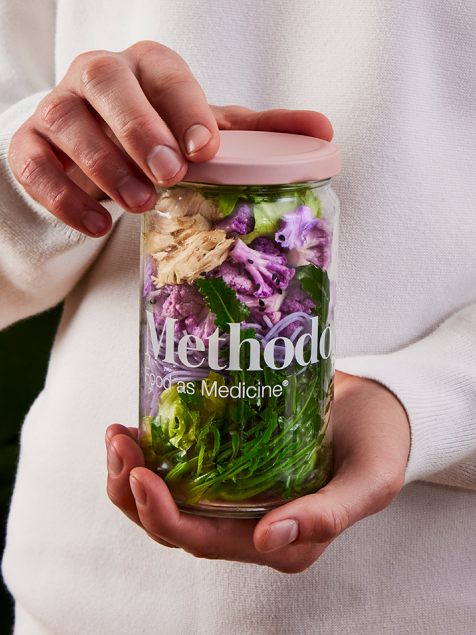A pair of hands holding a jar of Methodology food.