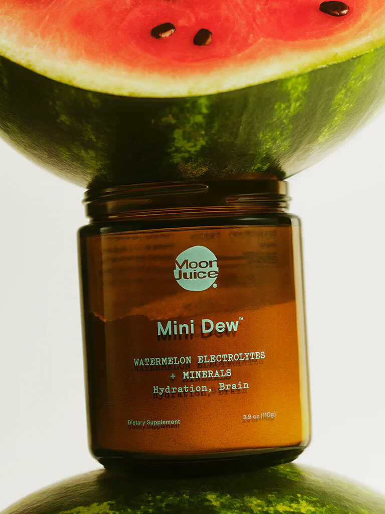 An open jar of Moon Juice Mini Dew under a watermelon.