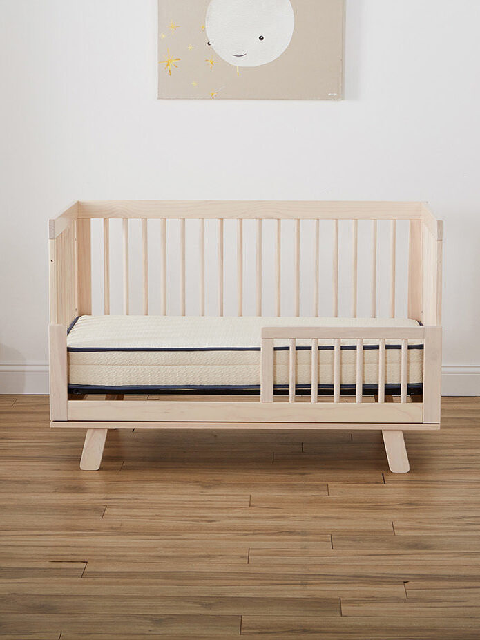 A crib in a room with a wooden floor.