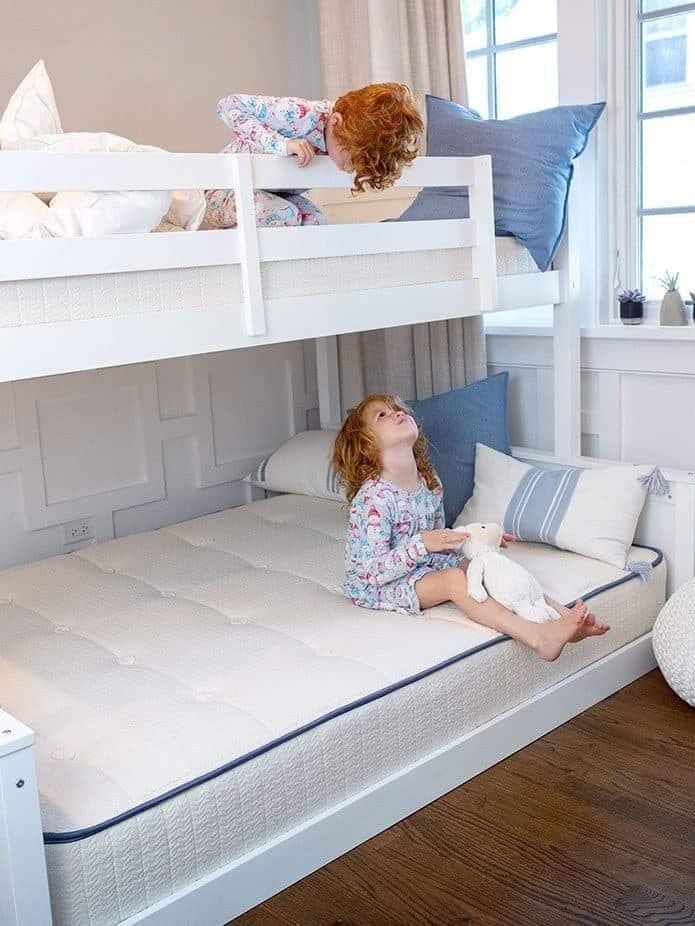 Two children on a bunk bed, one looking down, while the other looks up, both at each other. My Green Mattresses are fitted on both levels of the bunk bed 