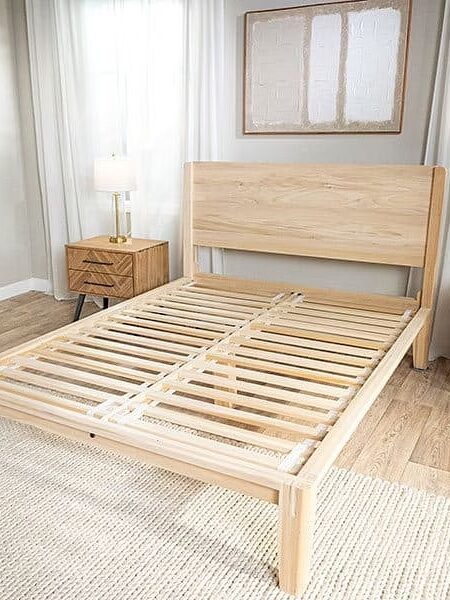 A wooden bed frame with slats in a bedroom.