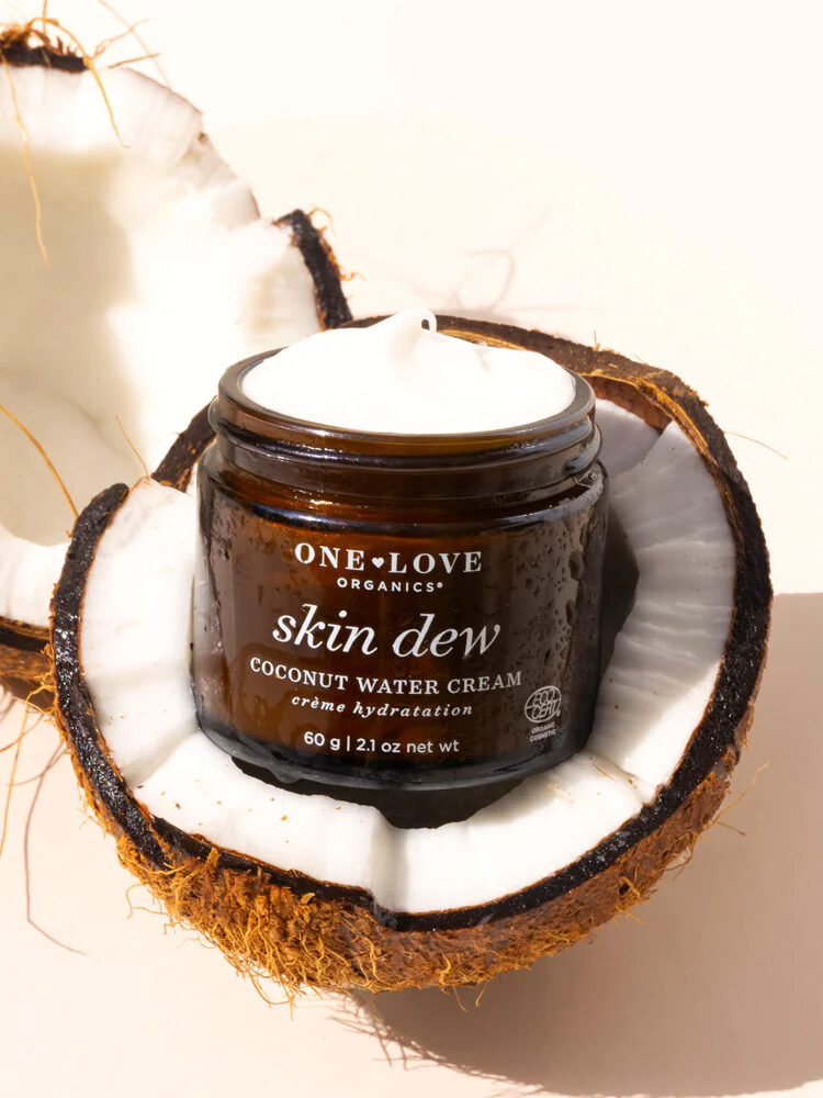 A jar of One Love Organics Face Cream in an open coconut. 