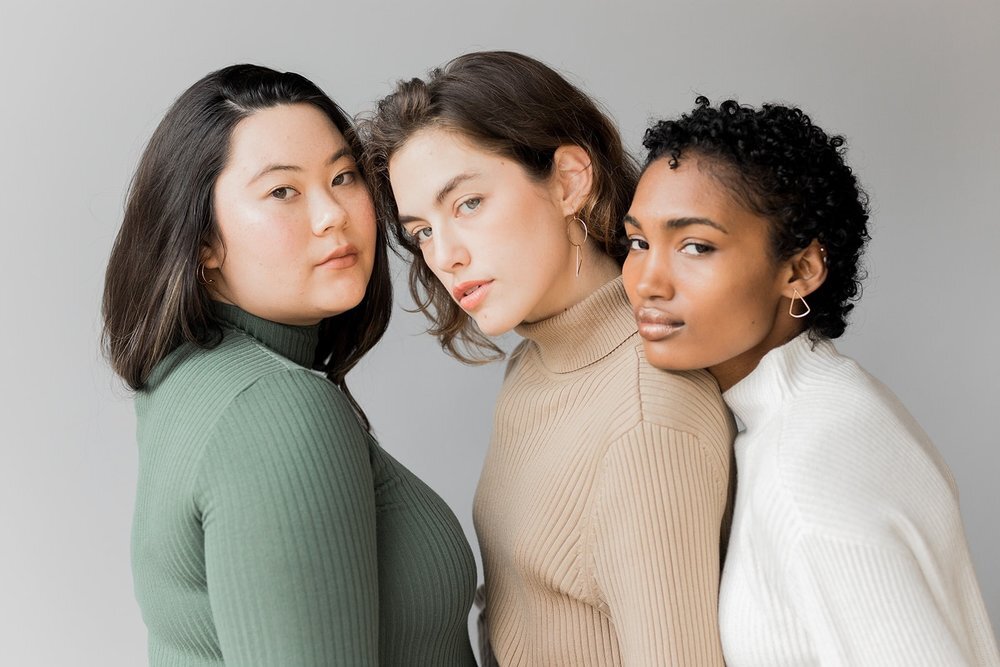 Three women in turtleneck sweaters posing for a photo.