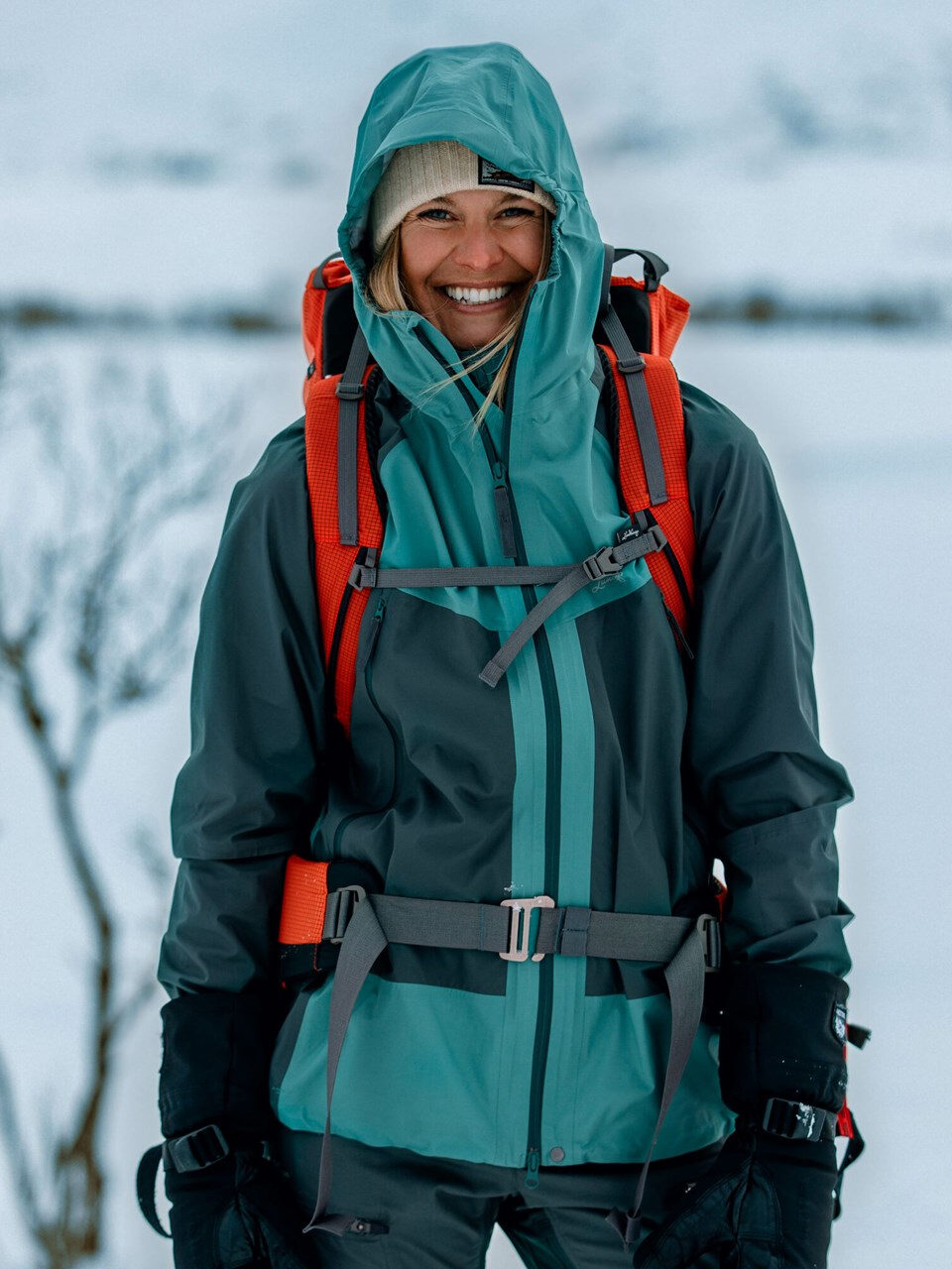 A woman in a ski jacket smiling in the snow.