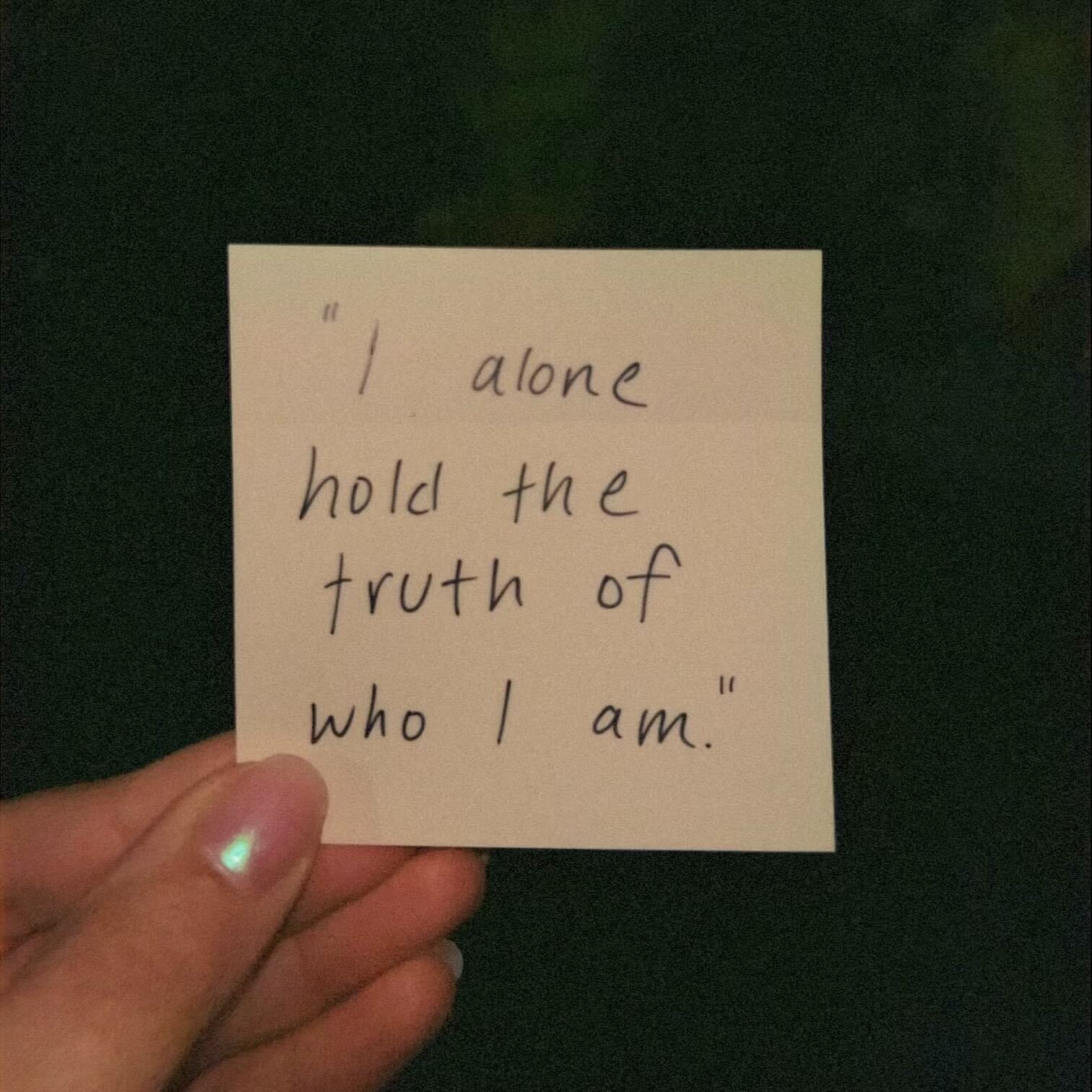 A sticky note held up reading, "I alone hold the trust of who I am". 