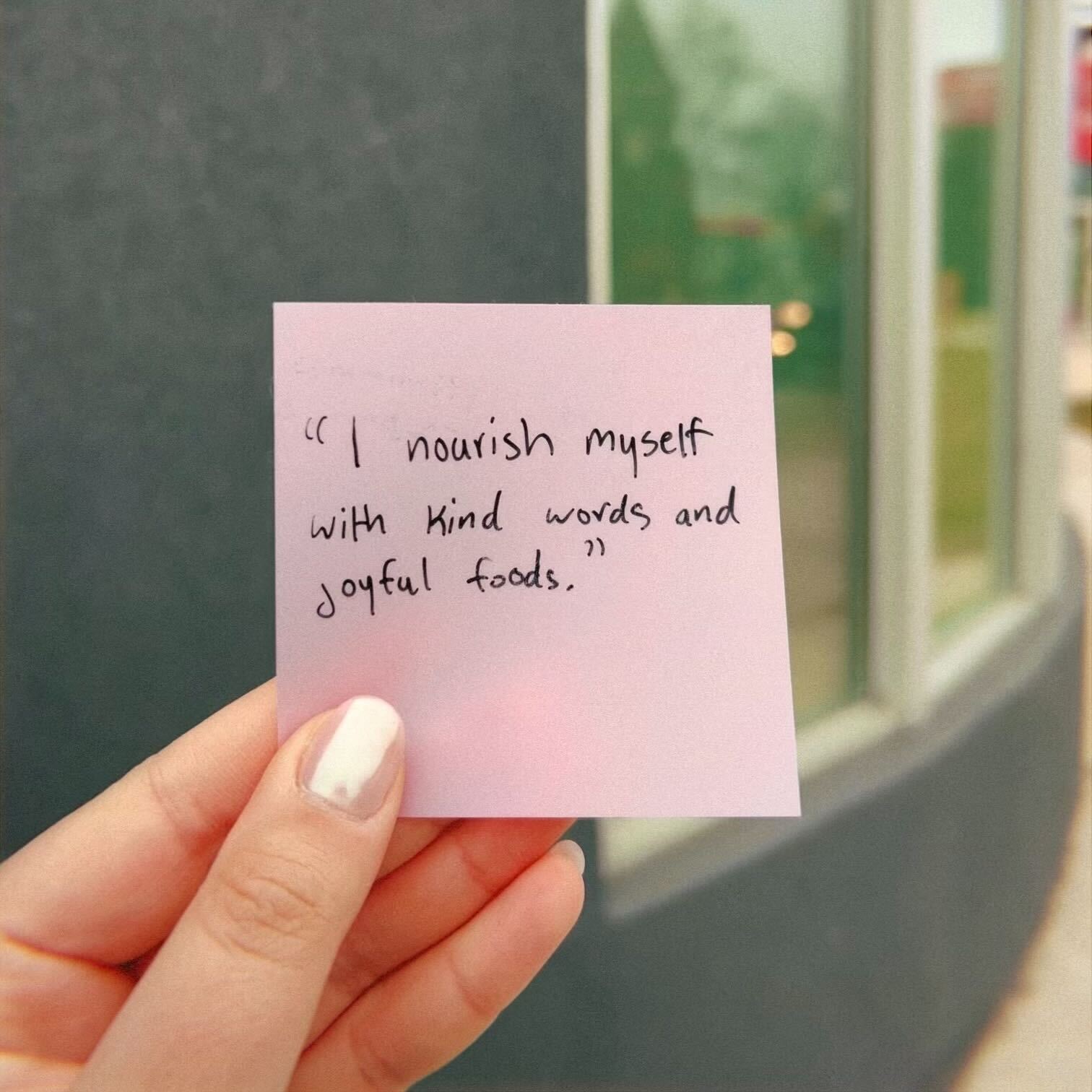A sticky note held up reading "I nourish myself with kind words and joyful foods".