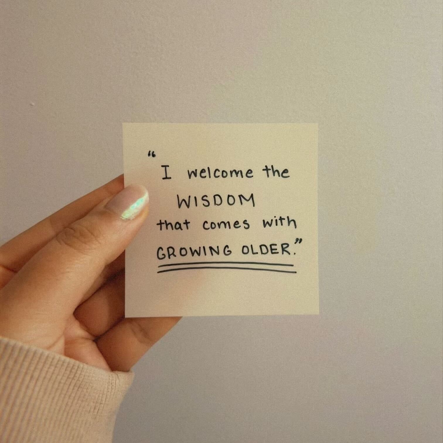 A sticky note held up, reading "I welcome the wisdom that comes with growing older".