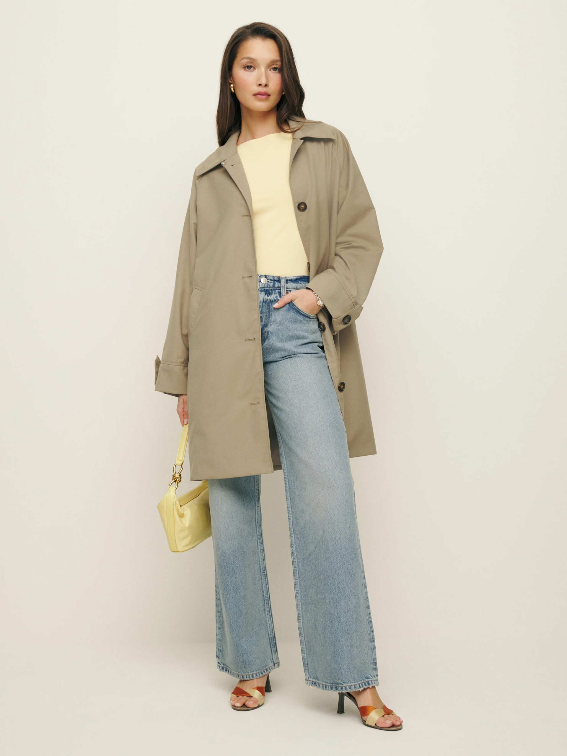A model wearing a trench coat and wide leg jeans.