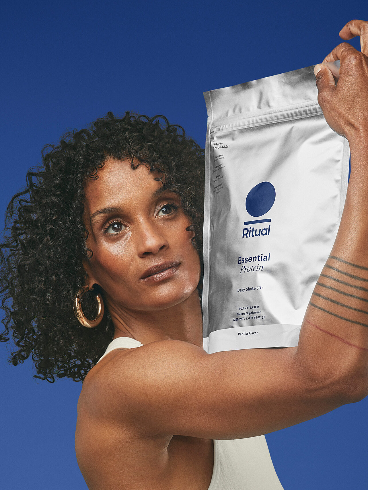 A model holding up a packet of Ritual's Essential Protein. 