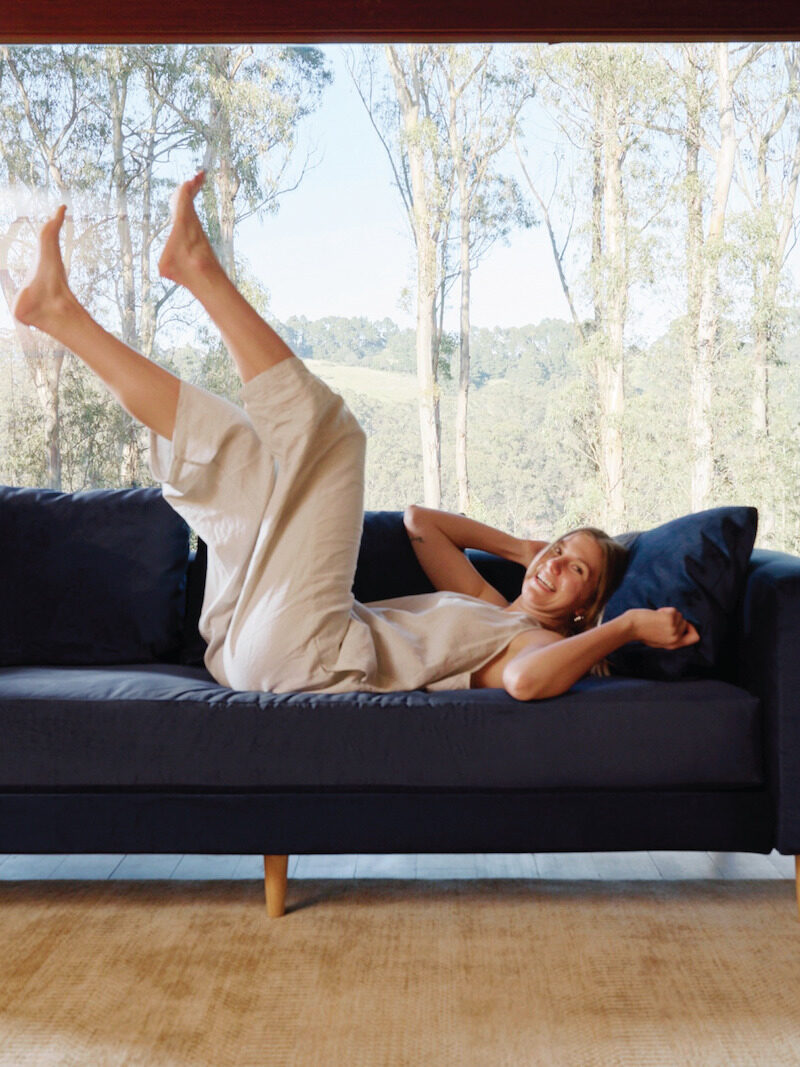 A model laying down with legs in the air on a Sabai sofa.