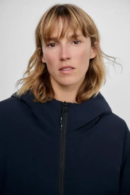 A woman wearing a navy hooded jacket.