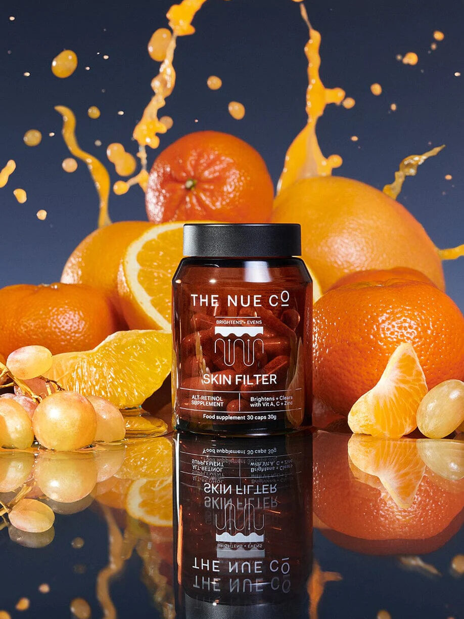 A jar of The Nue Co.'s Skin Filter, surrounded by oranges and grapes. 