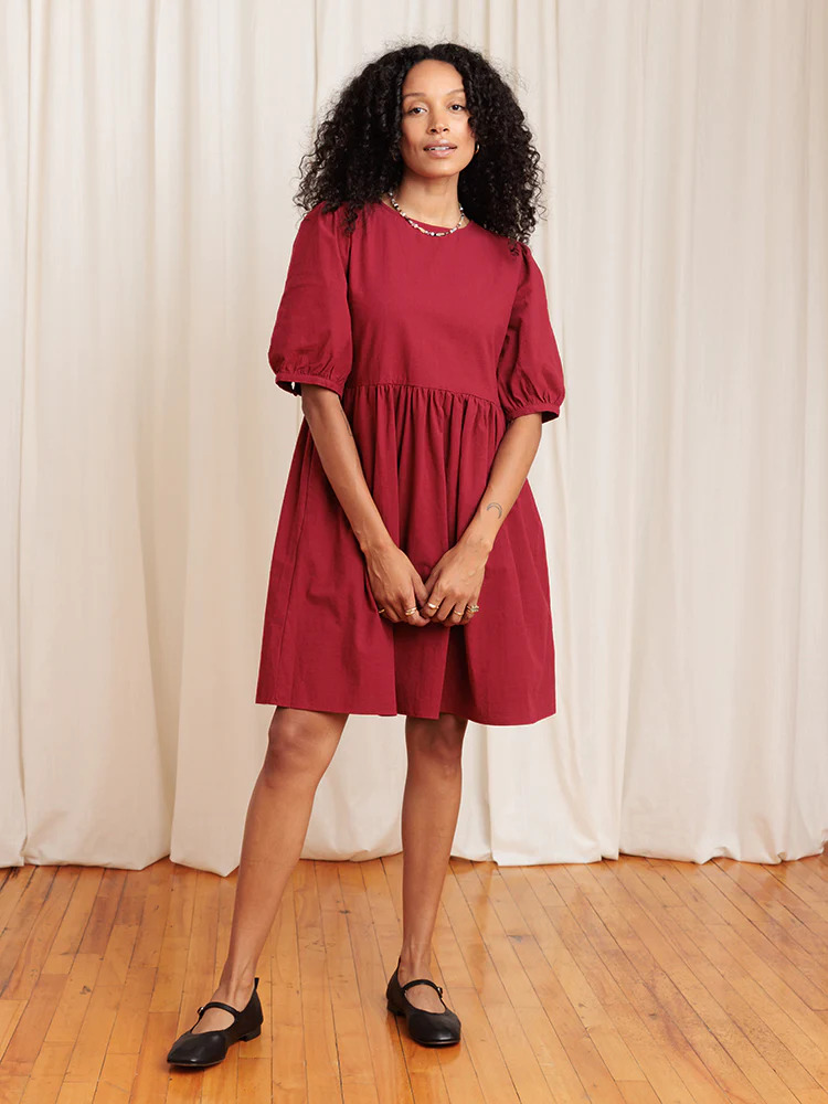 A black woman wearing a red dress and black shoes.
