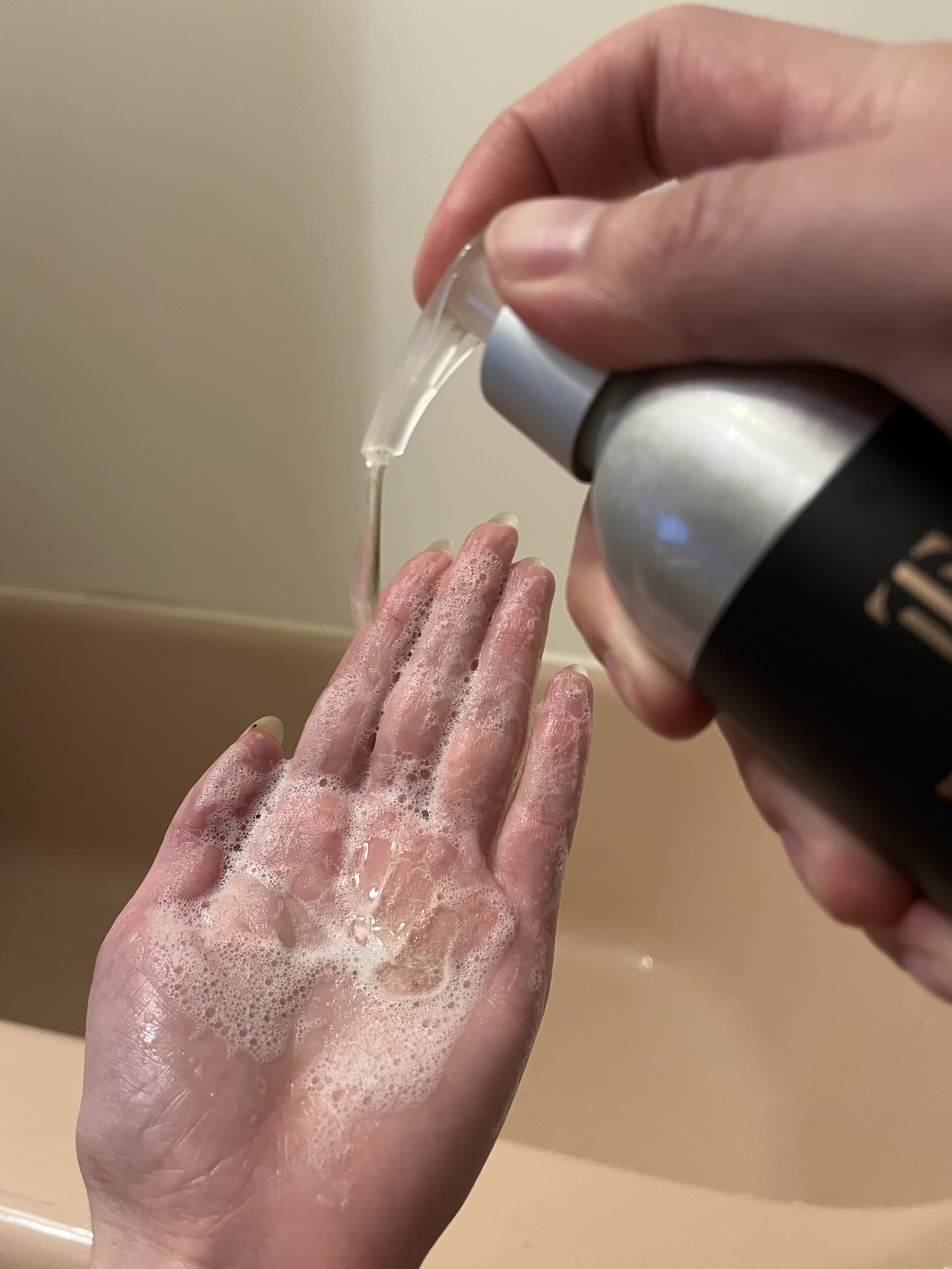 Dispensing liquid soap onto a hand above a sink.