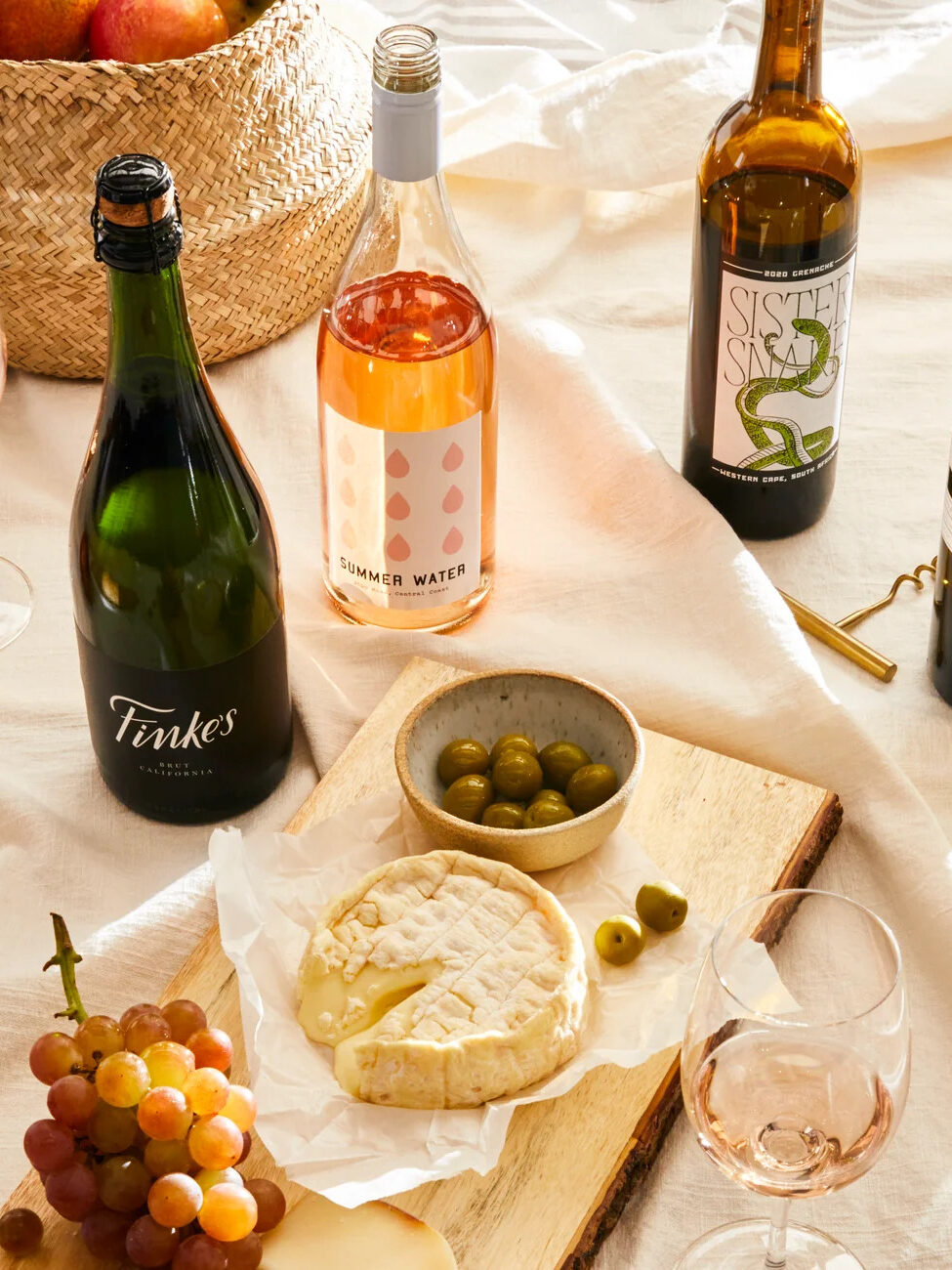 A charcuterie board surrounded by a variety of wines from Winc.