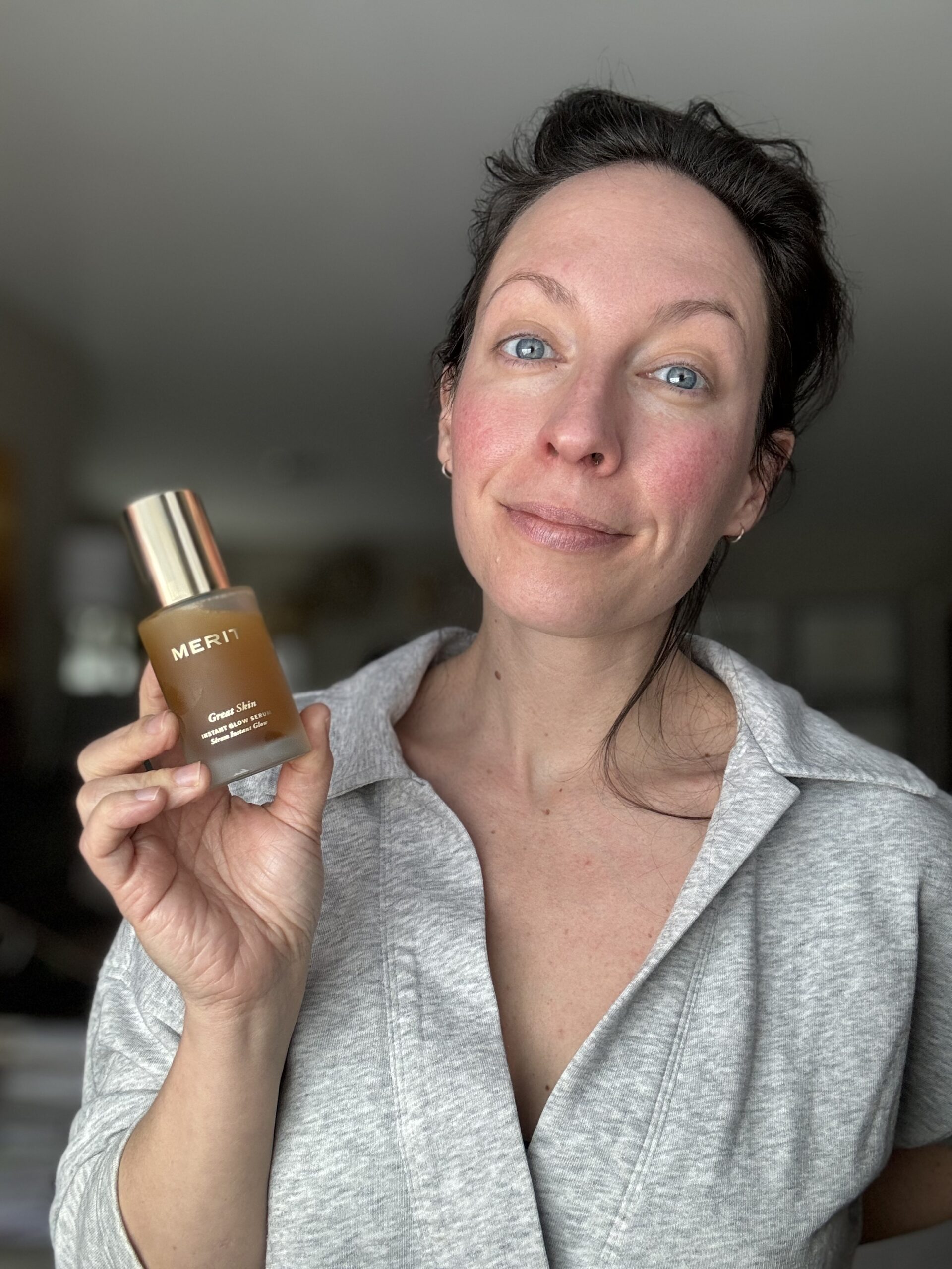 Woman holding a skincare product with a subtle smile.