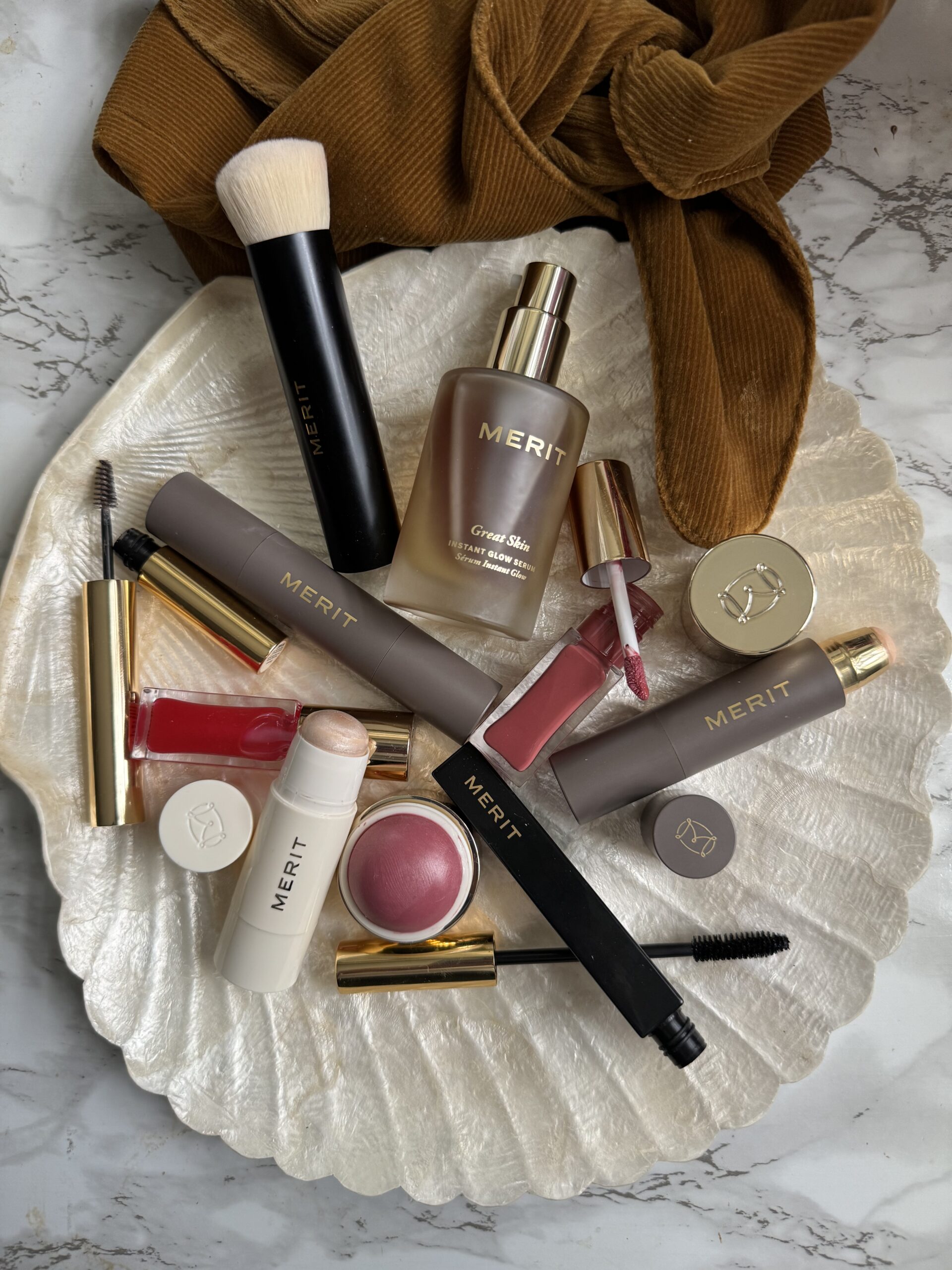 An assortment of cosmetics including foundation, lipstick, and mascara artfully arranged on a white surface.