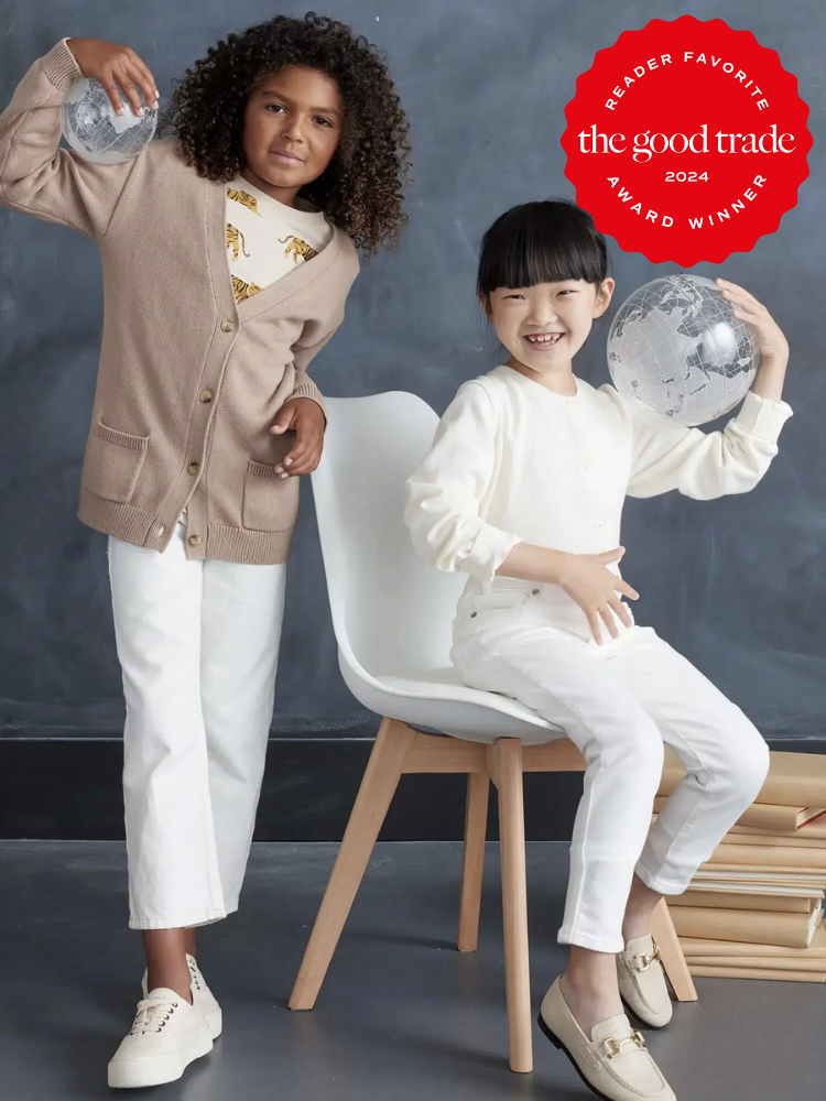 Two children are sitting on a chair with a globe in the background.