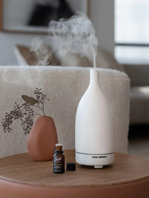 A white Saje diffuser, with a Saje essential oil next to it. 
