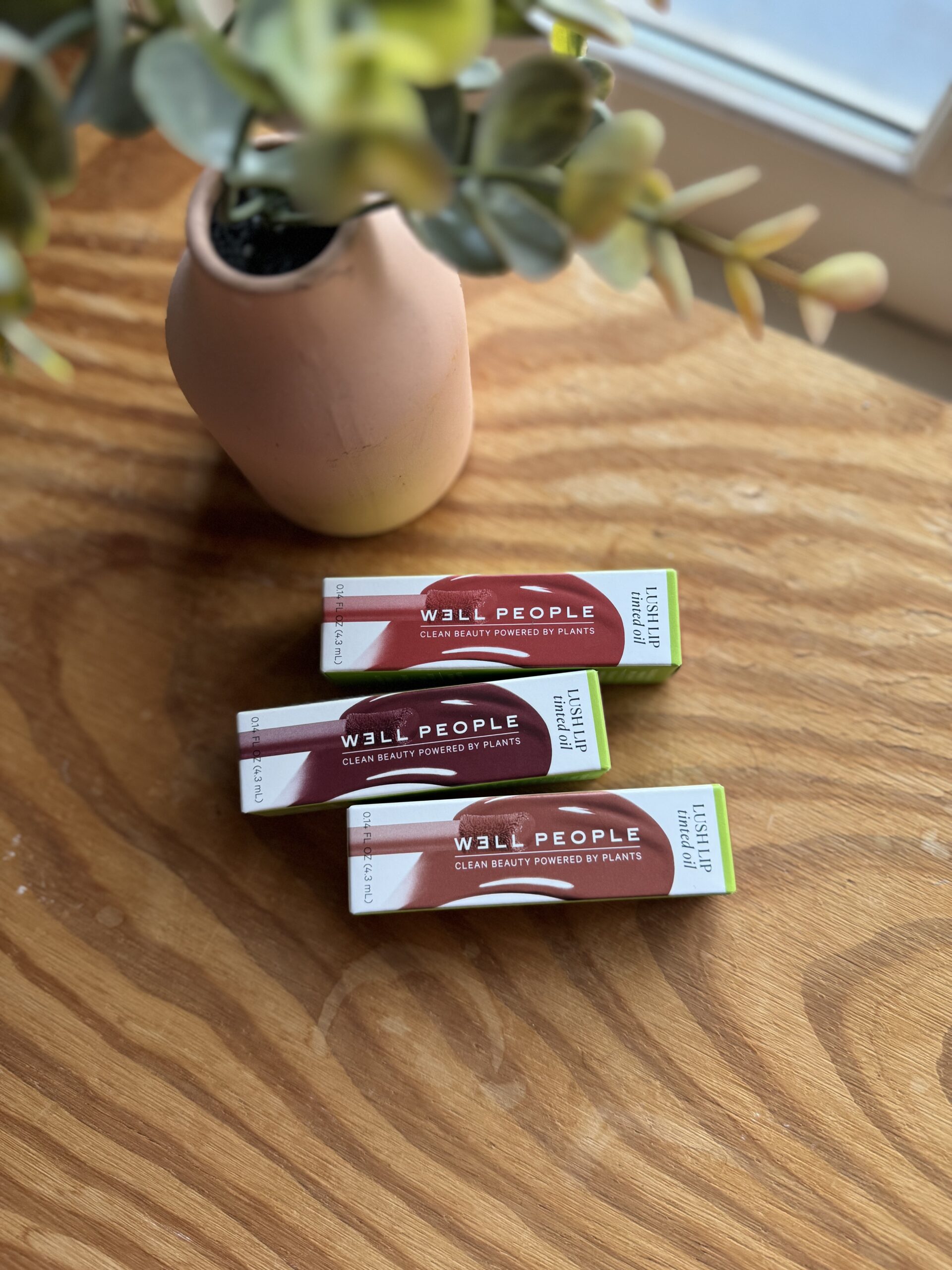 Three tubes of lip balm sitting on a wooden table.