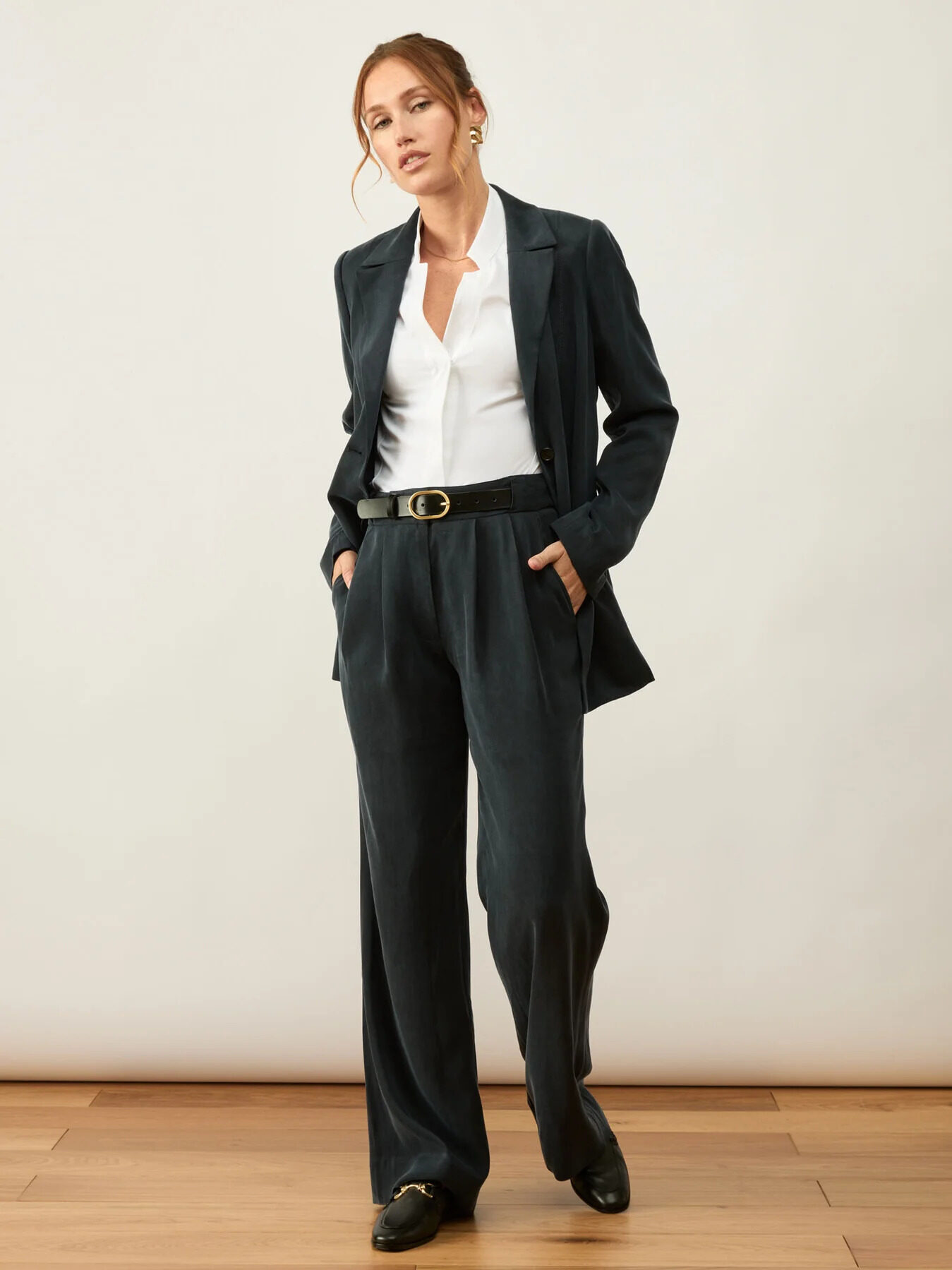 The model is wearing a white shirt and black trousers.
