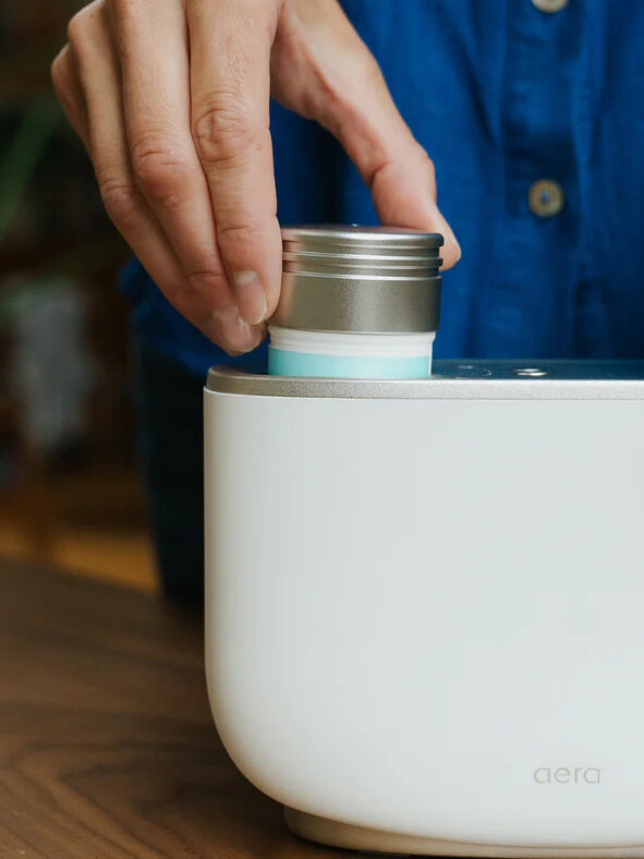 A close up of a model refilling an Aera diffuser. 