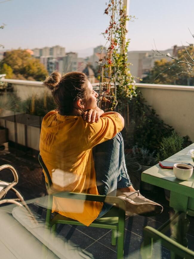 A man sitting on a chair on a balcony overlooking a city.