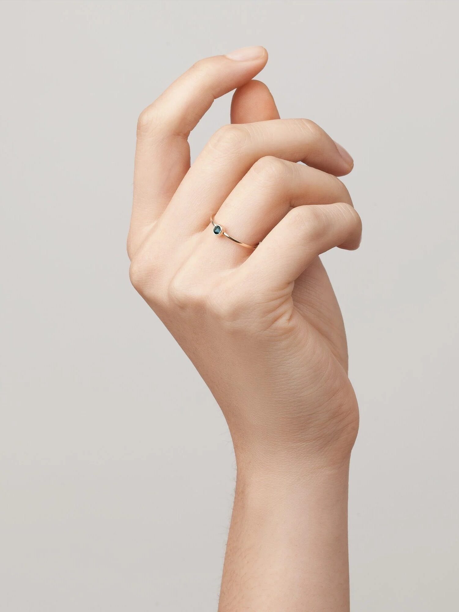 A close-up image of a person's hand making an 'ok' gesture with fingers touching to form a circle, adorned with a small ring.