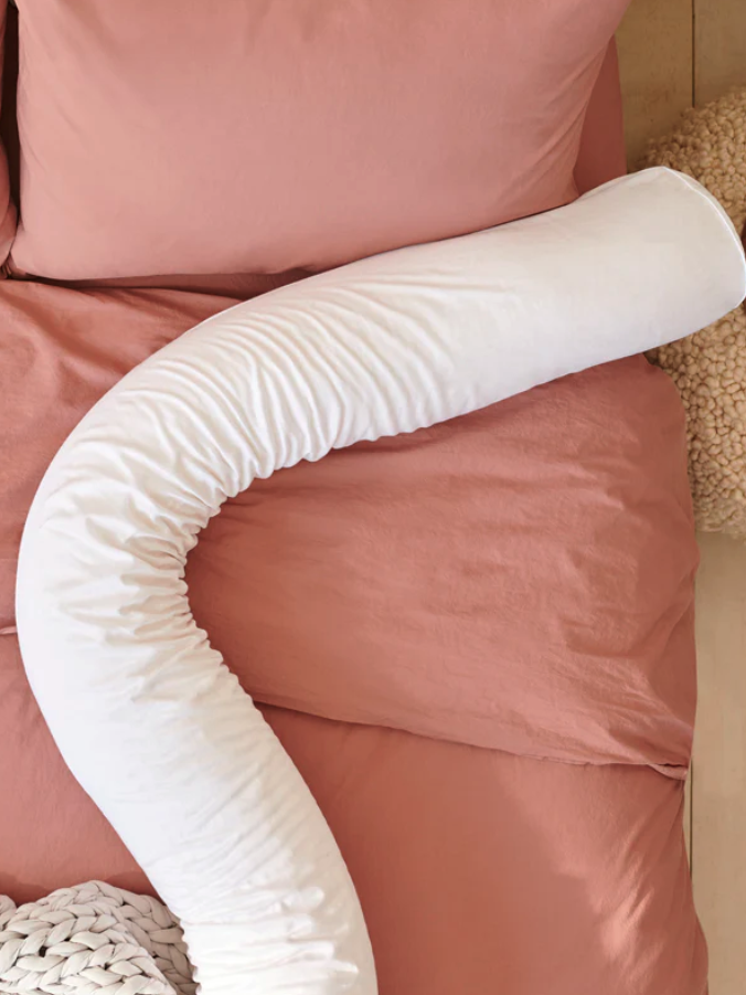 A bed with a white swan shaped pillow on it.