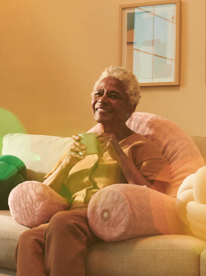 A woman sitting on a couch with pillows.