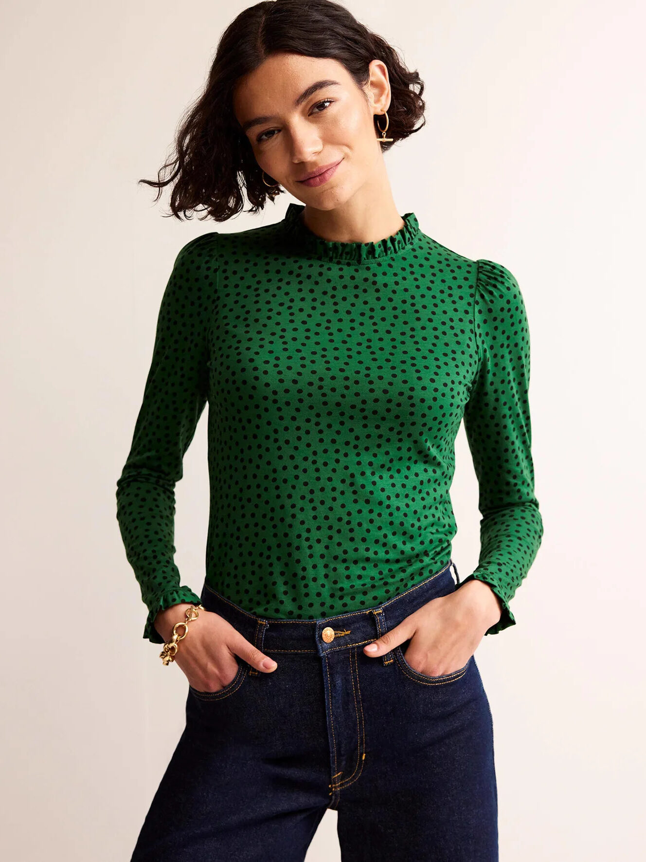 A woman wearing a green polka dot top and jeans.