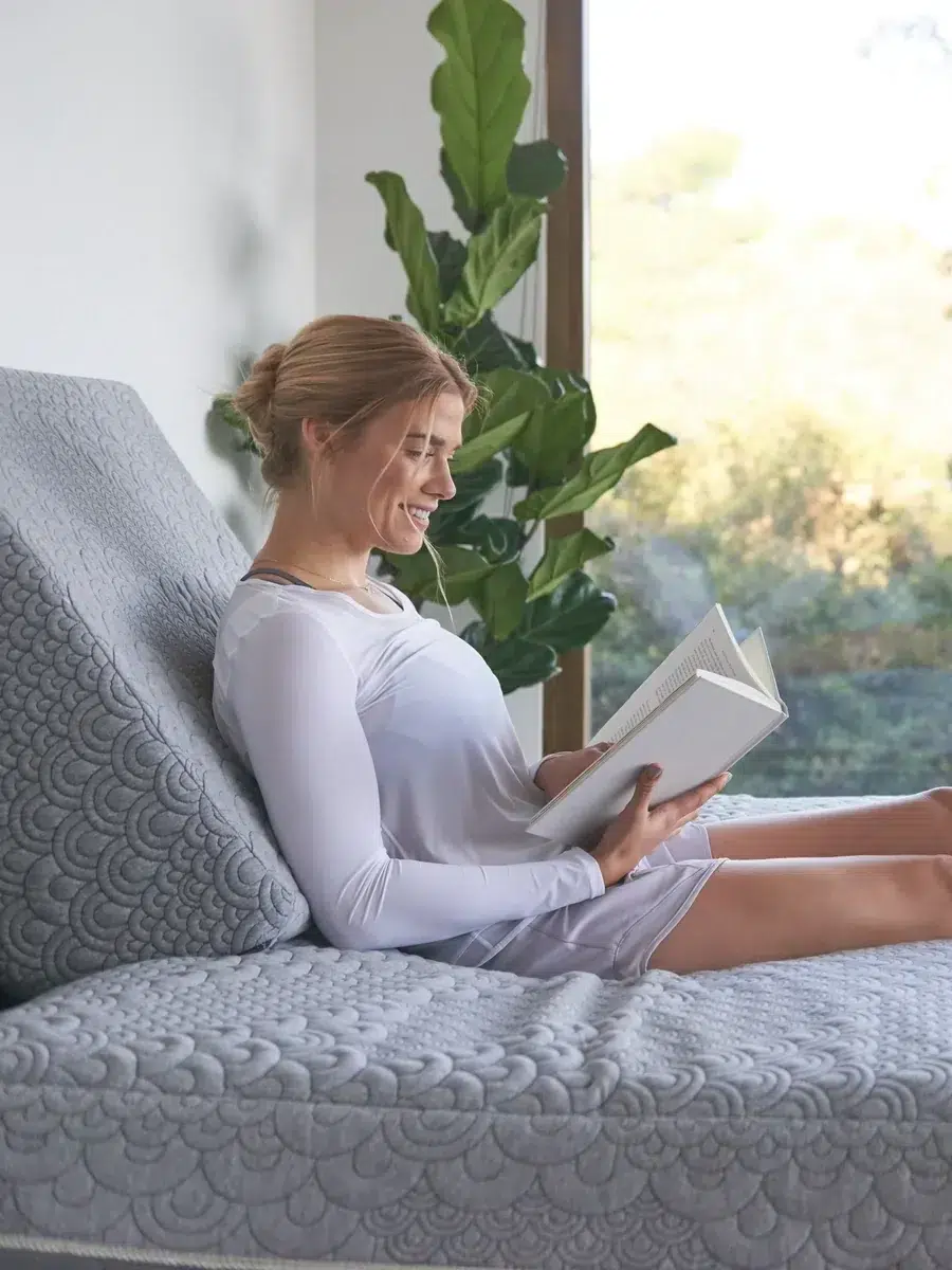 A woman reading a book on a mattress.
