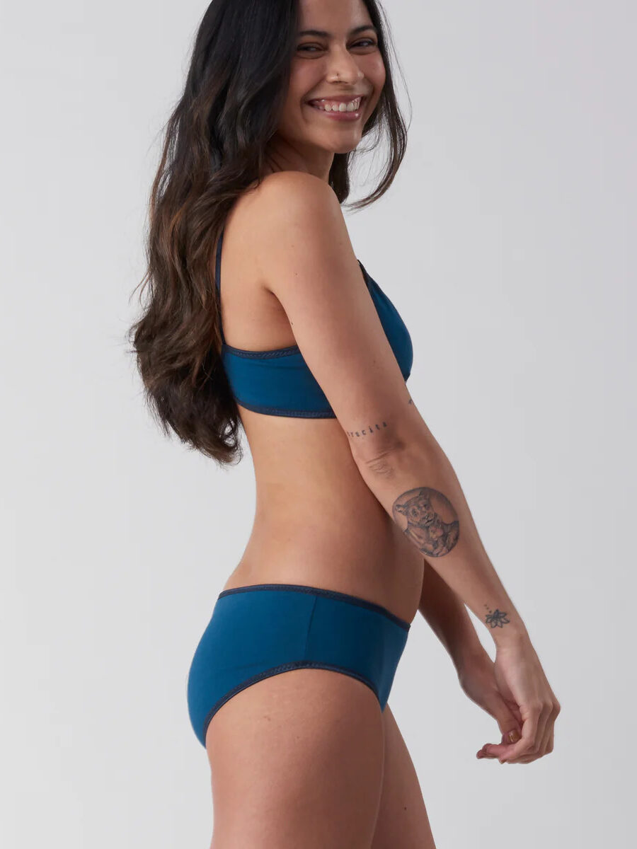 A woman wearing a blue lingerie set with tattoos.
