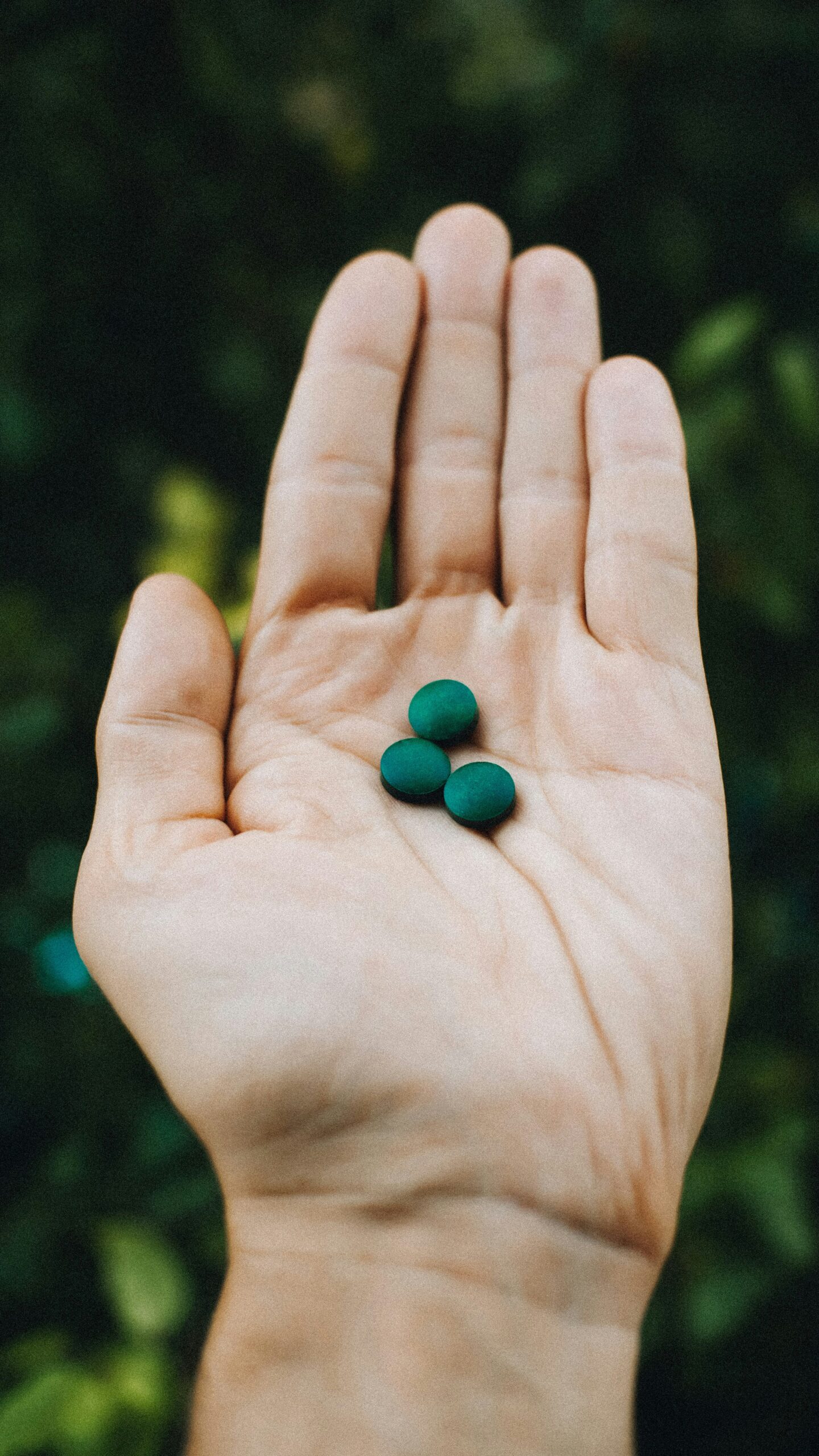 Two green pills in a person's hand.