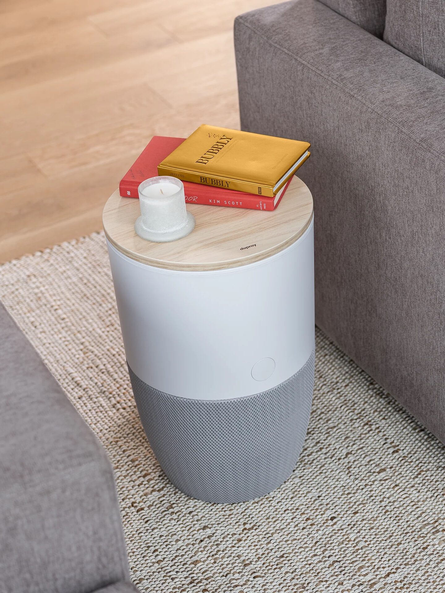 Modern minimalist side table with storage, featuring a book and cup on top, beside a gray sofa.