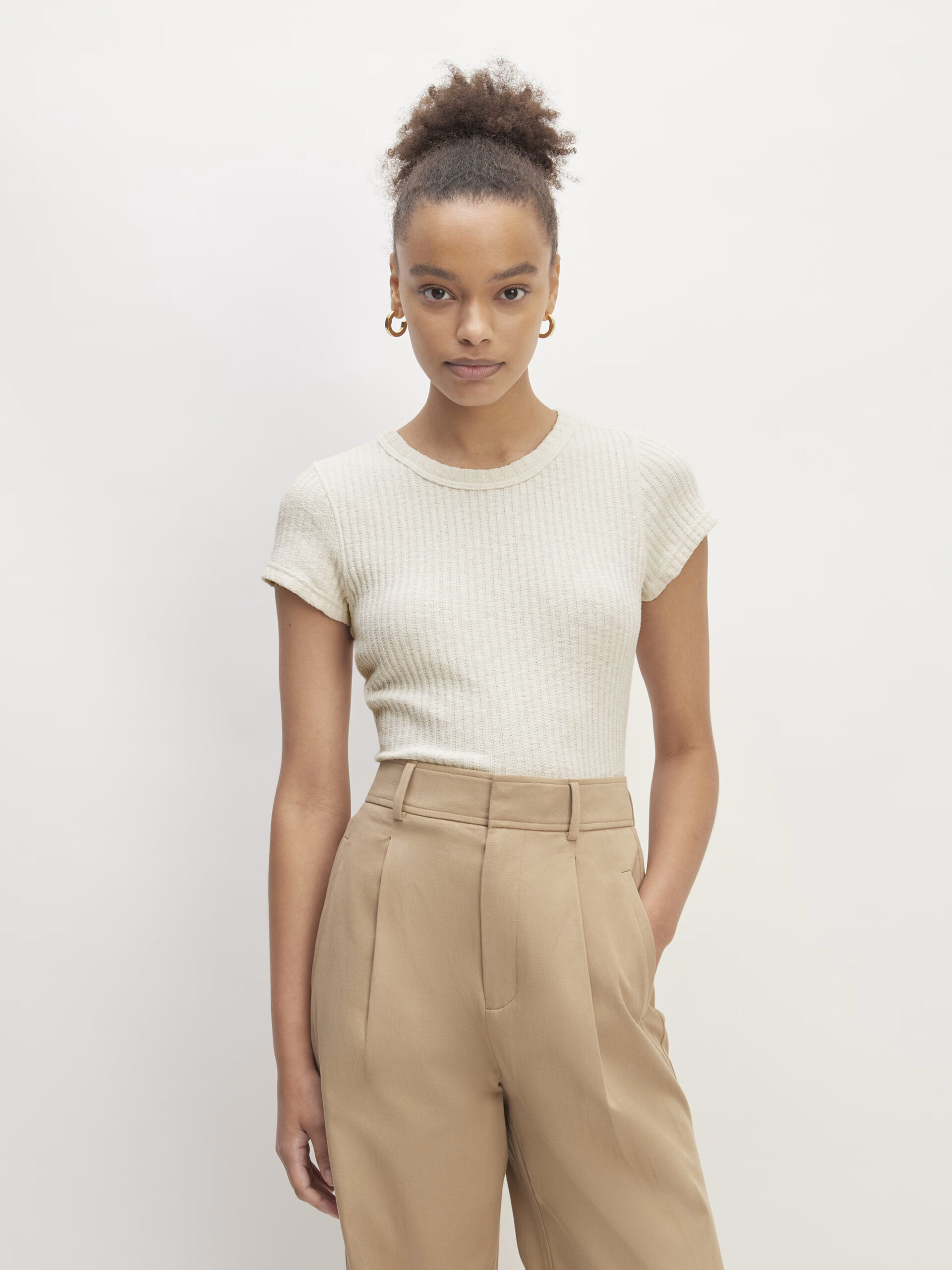 The model is wearing beige trousers and a white t - shirt.