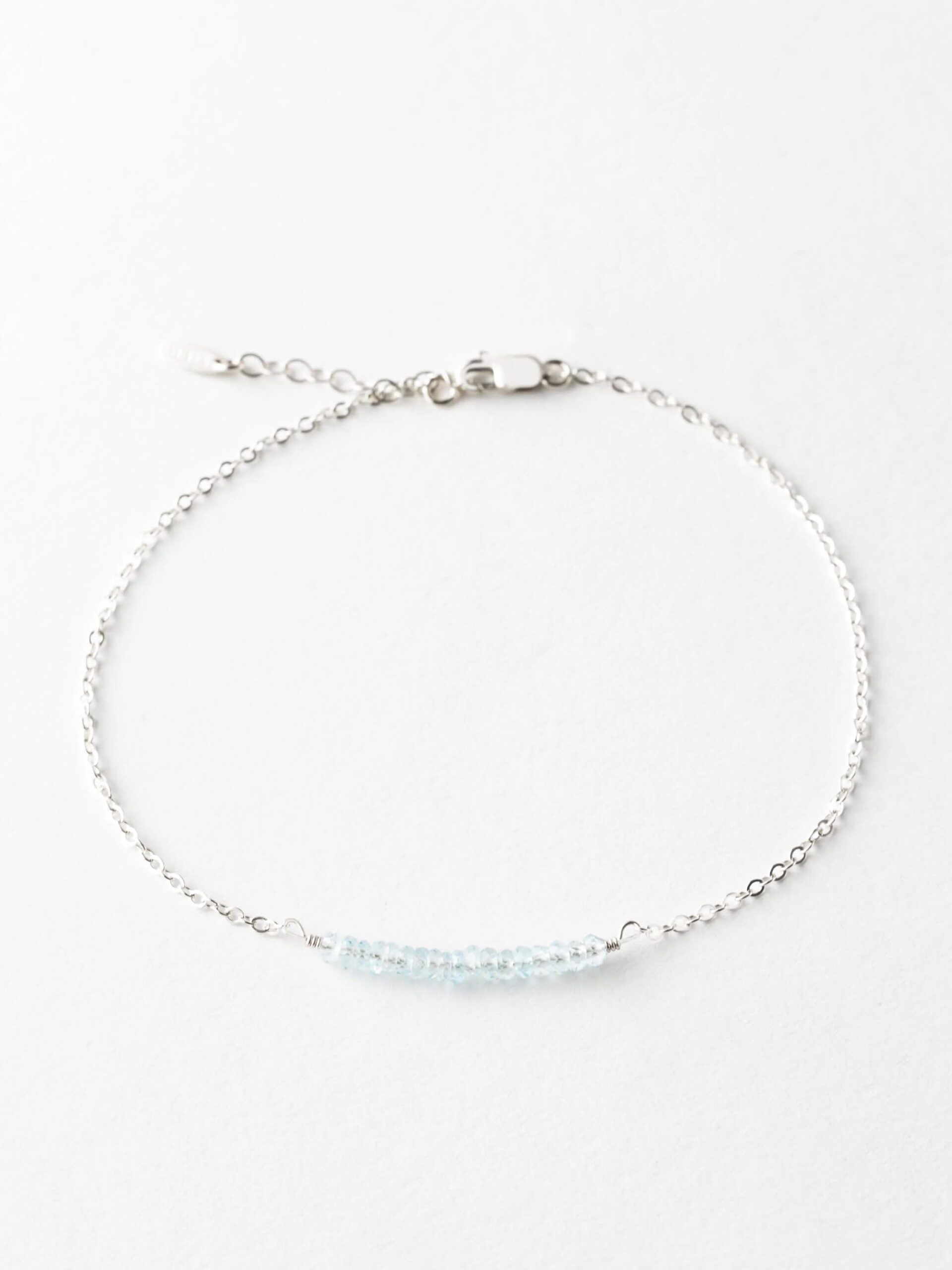 Silver chain bracelet with a central section of blue beads on a white background.