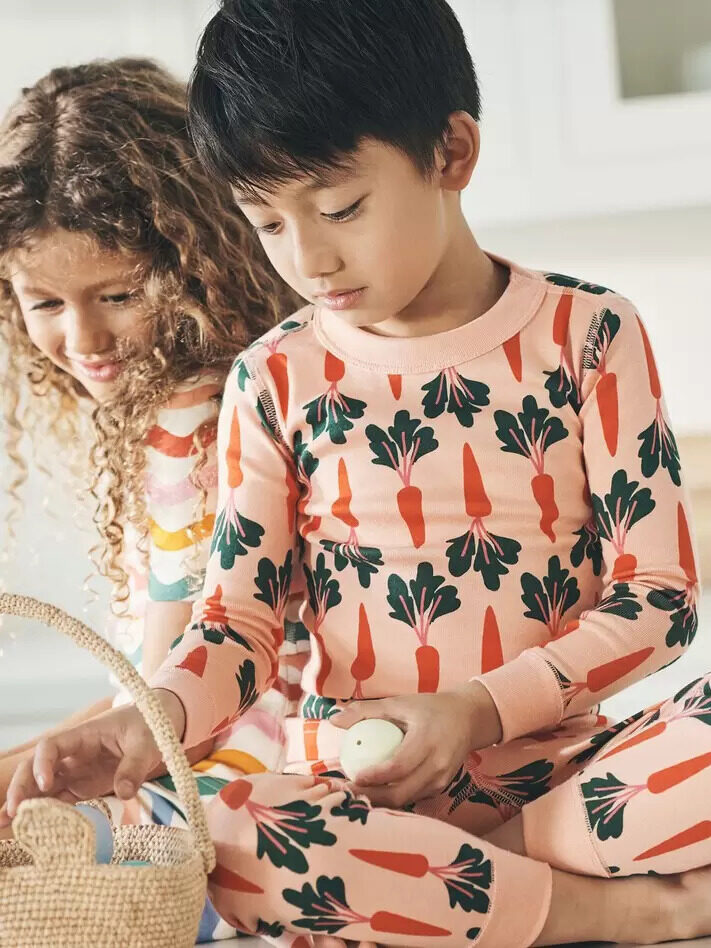 Two children playing with an easter basket on the floor.