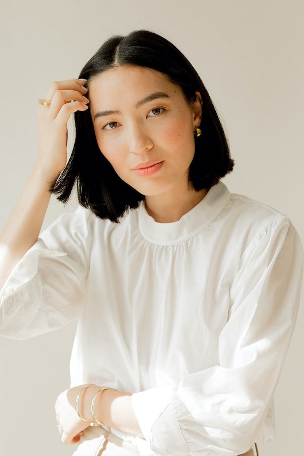 A woman wearing a white blouse and tan pants.