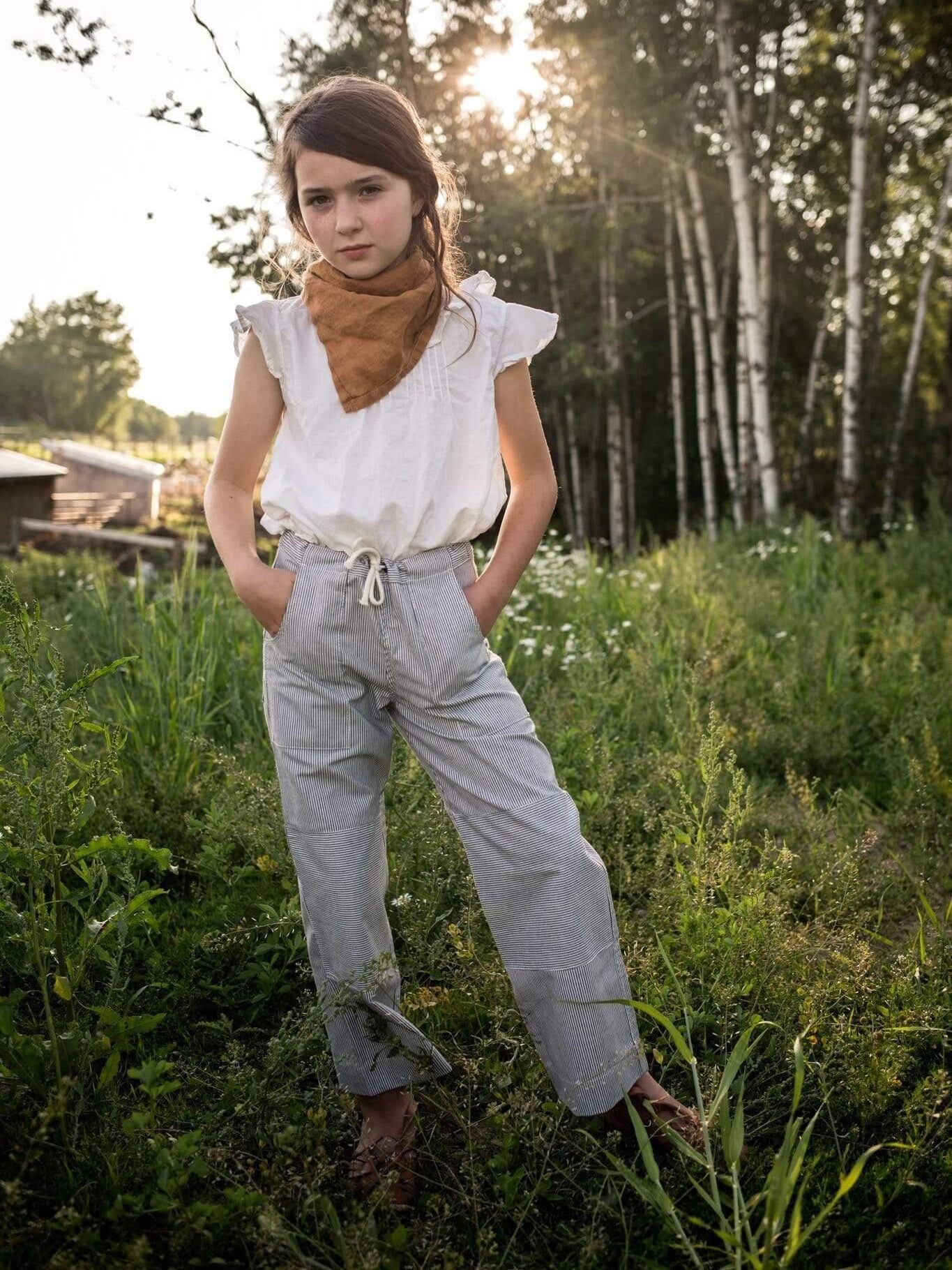 A little girl standing in a field wearing a scarf.