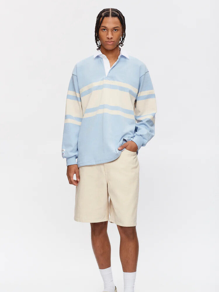 The model is wearing a blue and beige striped sweater and shorts.