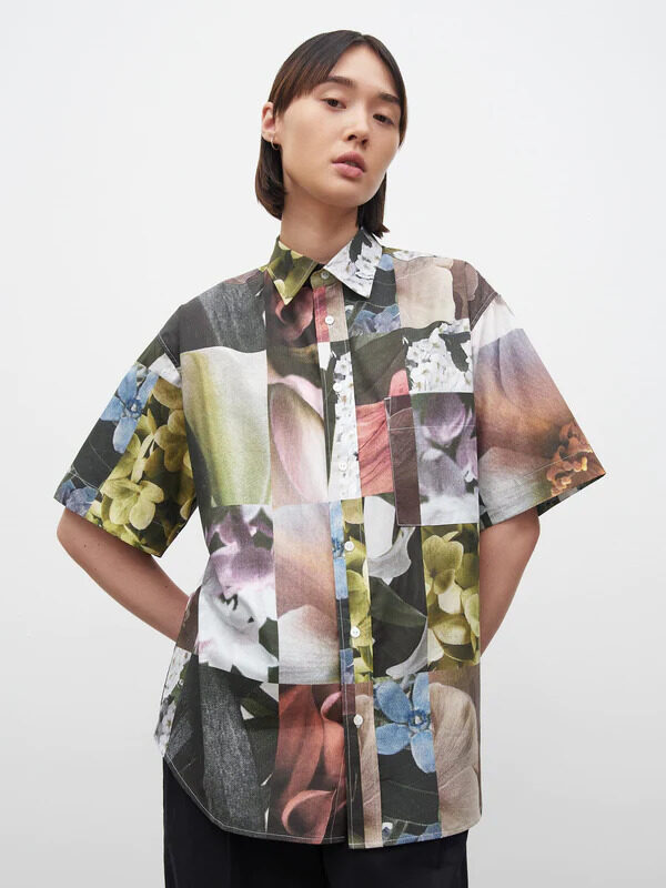 The model is wearing a shirt with multi - colored flowers on it.