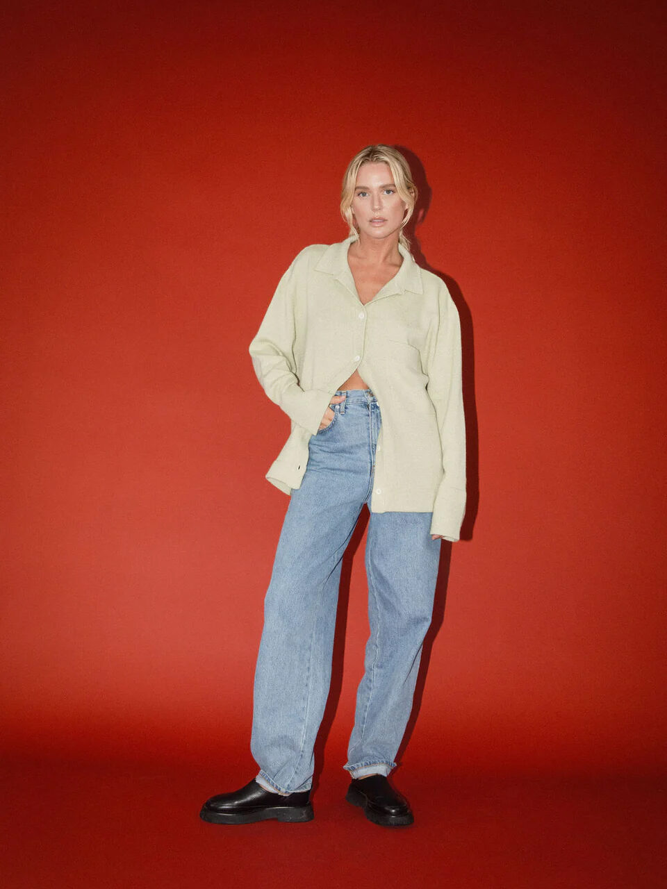 Woman in casual attire standing against a red background.