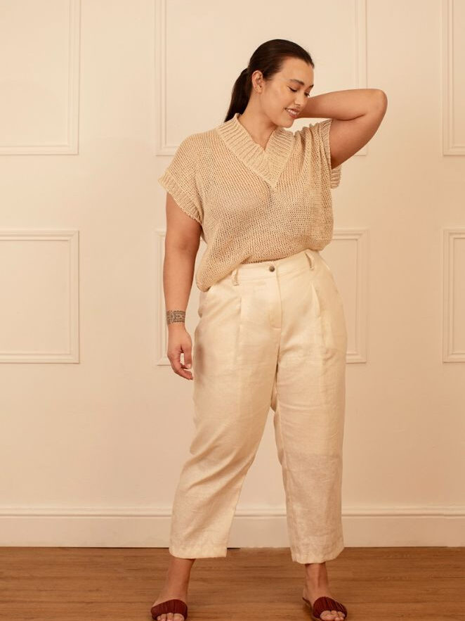 Woman in a casual beige outfit posing with her hand on her elbow.