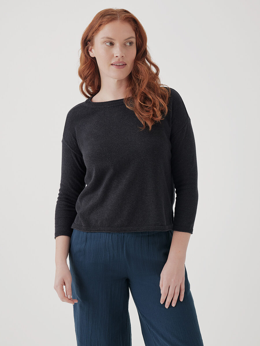 Woman posing in a simple black top and blue trousers.