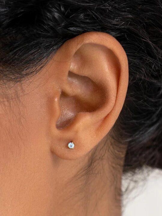 Close-up of a woman's ear with a diamond stud earring.