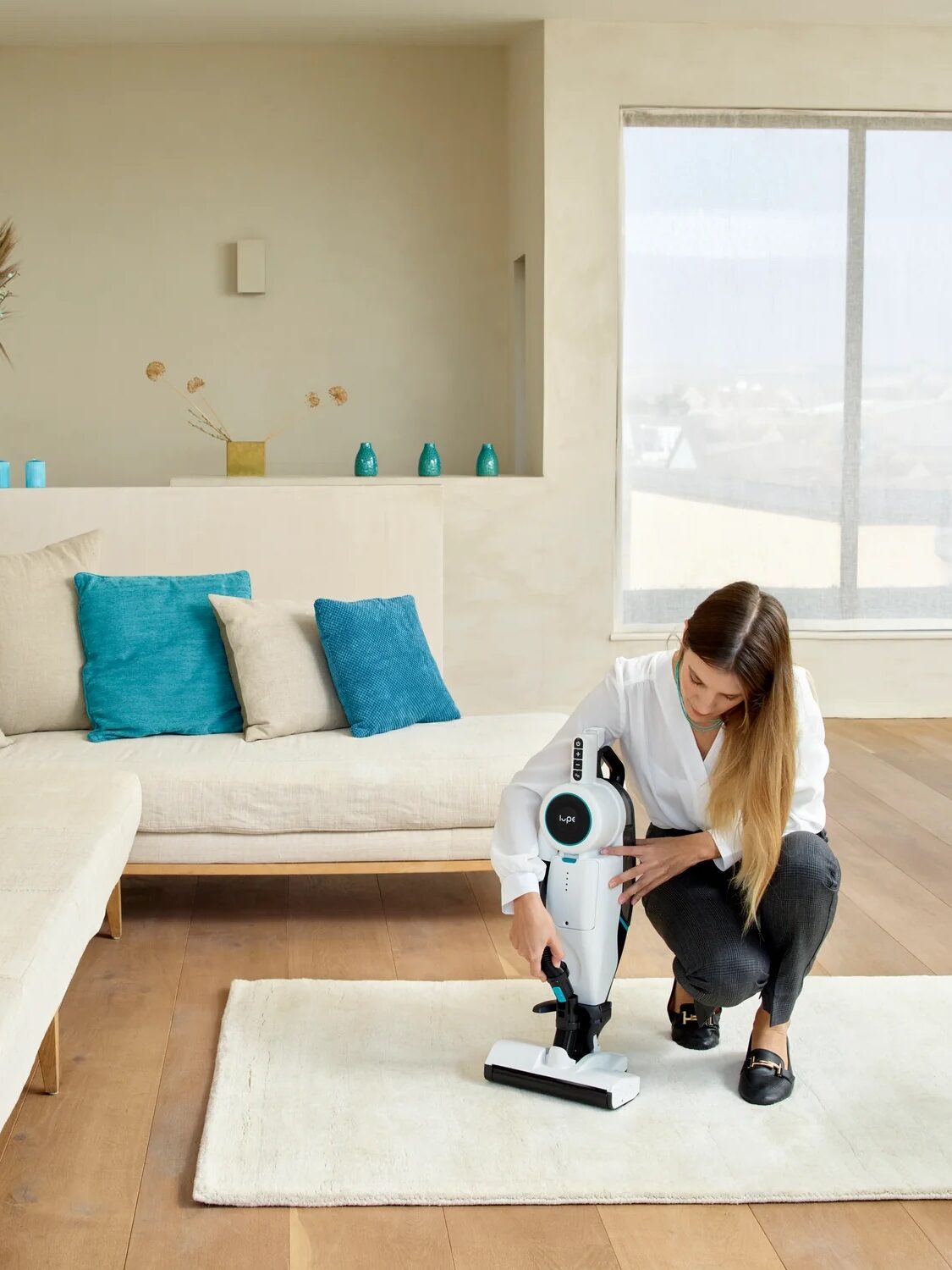 Woman setting up a robotic vacuum cleaner in a bright living room.