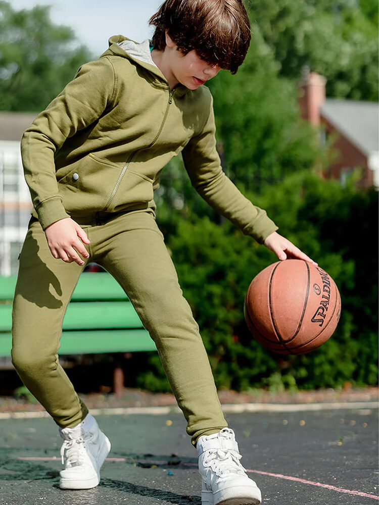A young boy wearing a green hoodie and jogging pants.