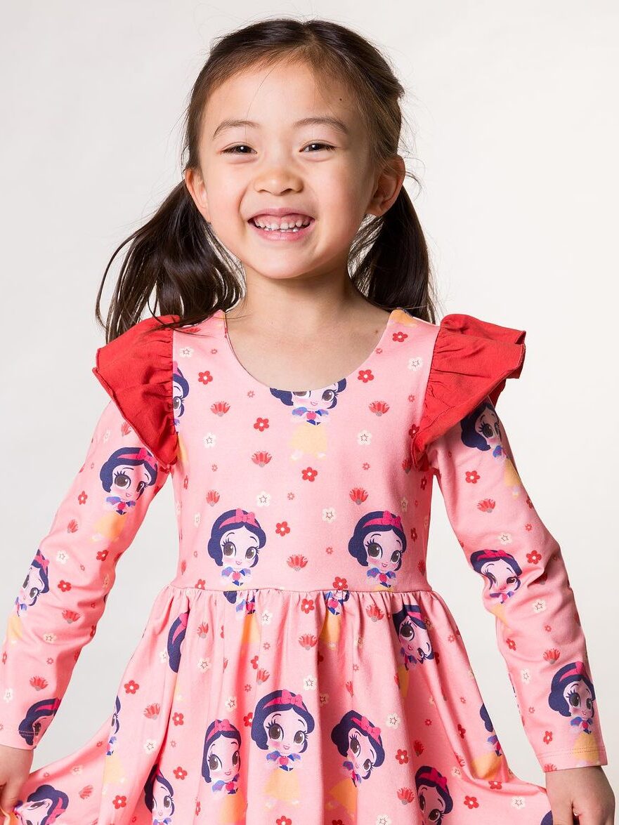 A little girl wearing a pink dress with a snow white print.