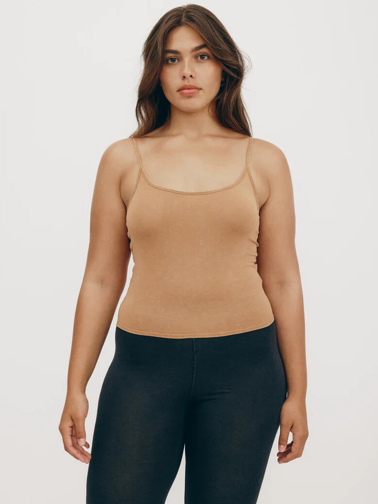 The model is wearing a camel tank top and black leggings.